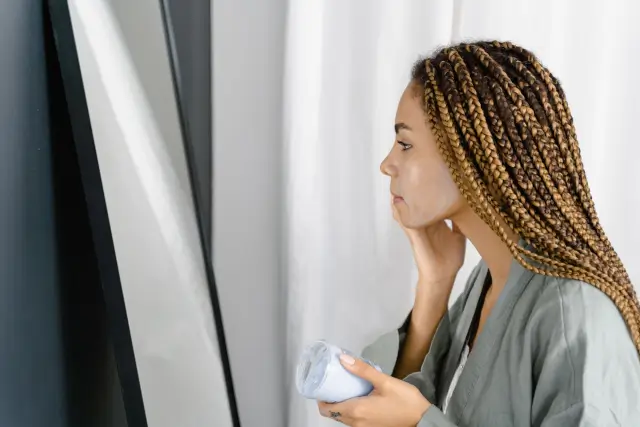Dettaglio di una donna che applica crema sul viso per una pelle in autunno più confortevole